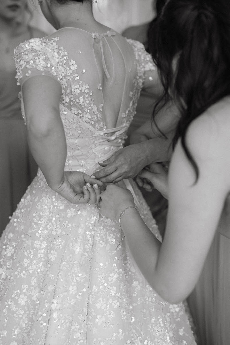woman helping bride zip up her dress