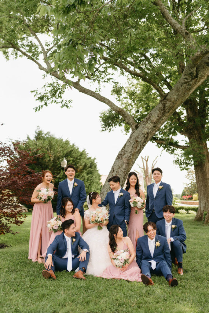 wedding party sitting and standing near a tree 