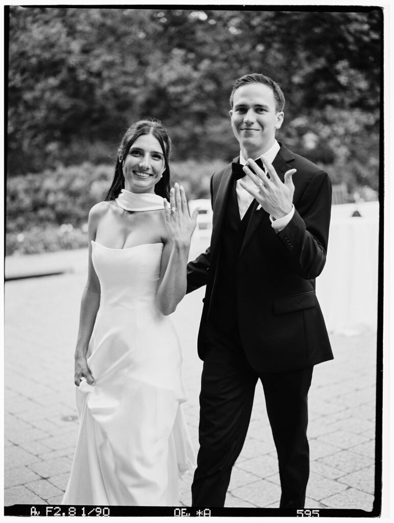 A newlywed couple shows off their new rings in passing on black and white film