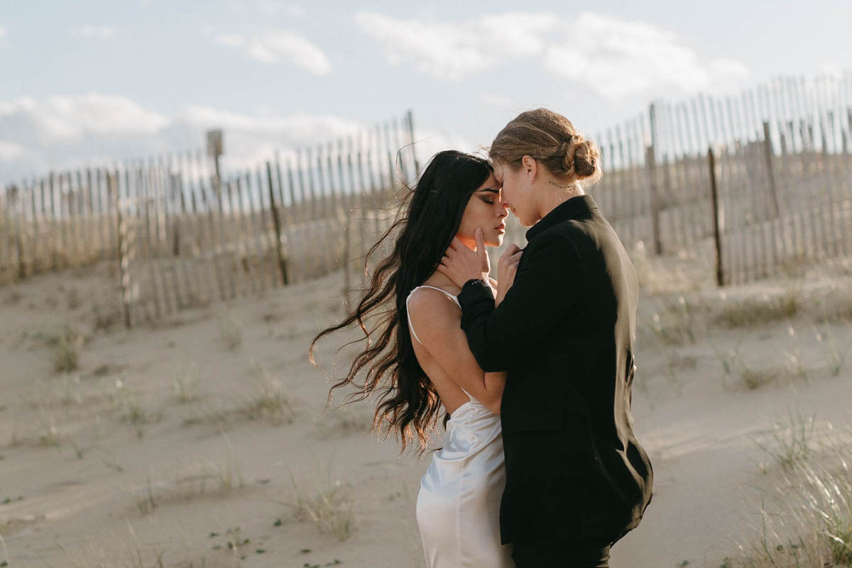 wedding couple standing close together about to kiss on the beach