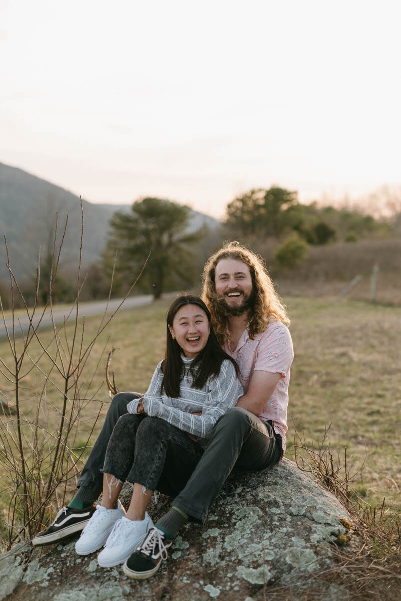 couple sitting with their arms around each other in a field