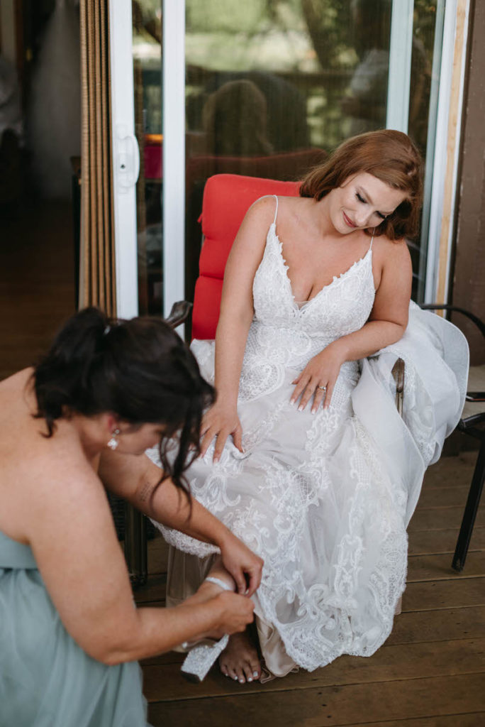 woman putting on a bride's shoe