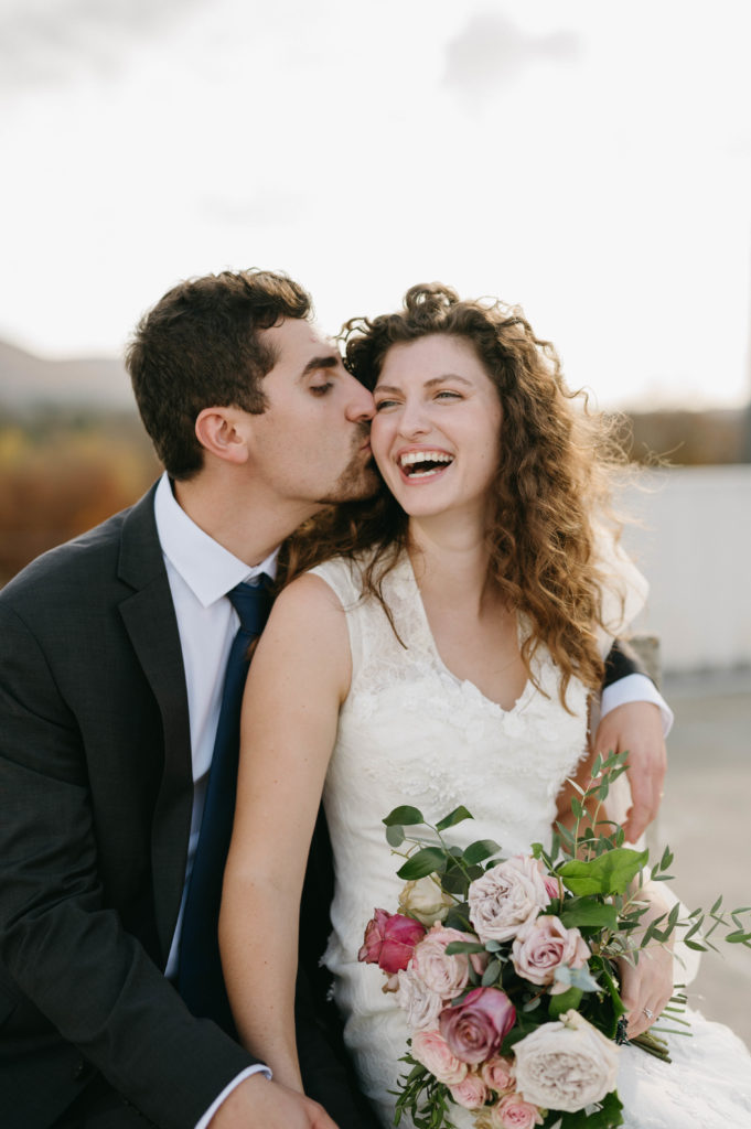 bride laughs as groom kisses her cheek