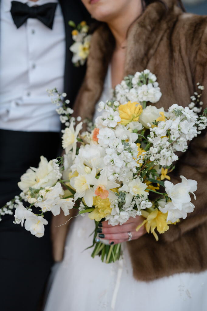 A whimsical and lush bouquet of white, yellow, and peach flowers 