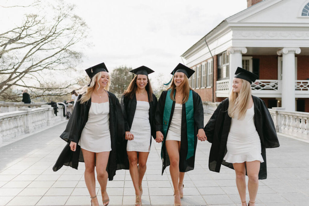 A group of friends holding hands and walking together in their graduation caps and gowns. 