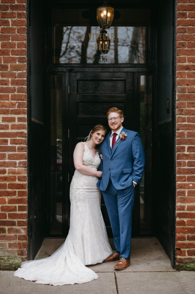A wedding couple standing in the doorway of a brick building.
