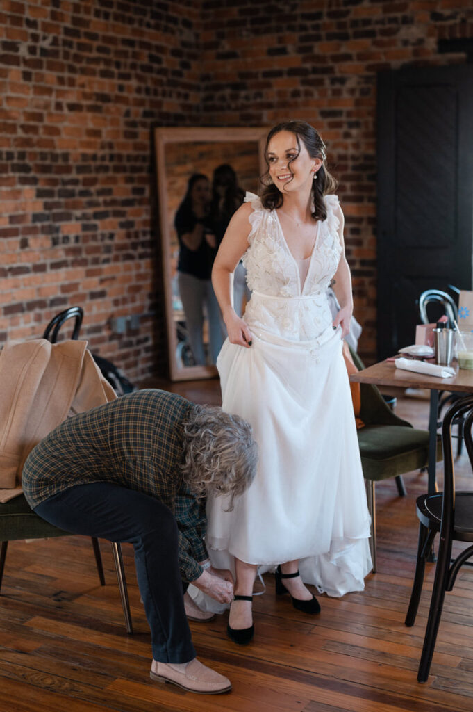 A person helping a bride put on her shoe.