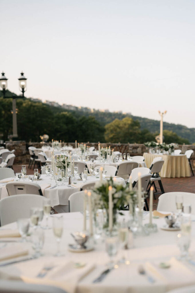 Circular wedding reception tables set up on a brick terrace. 