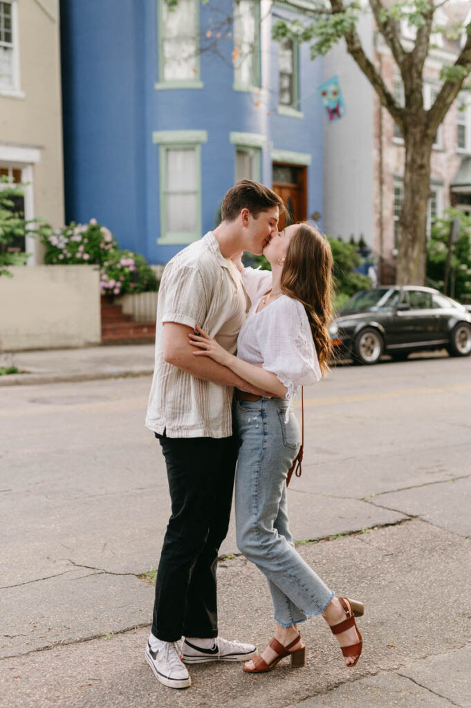 A couple kissing while standing in the street of a small city. 