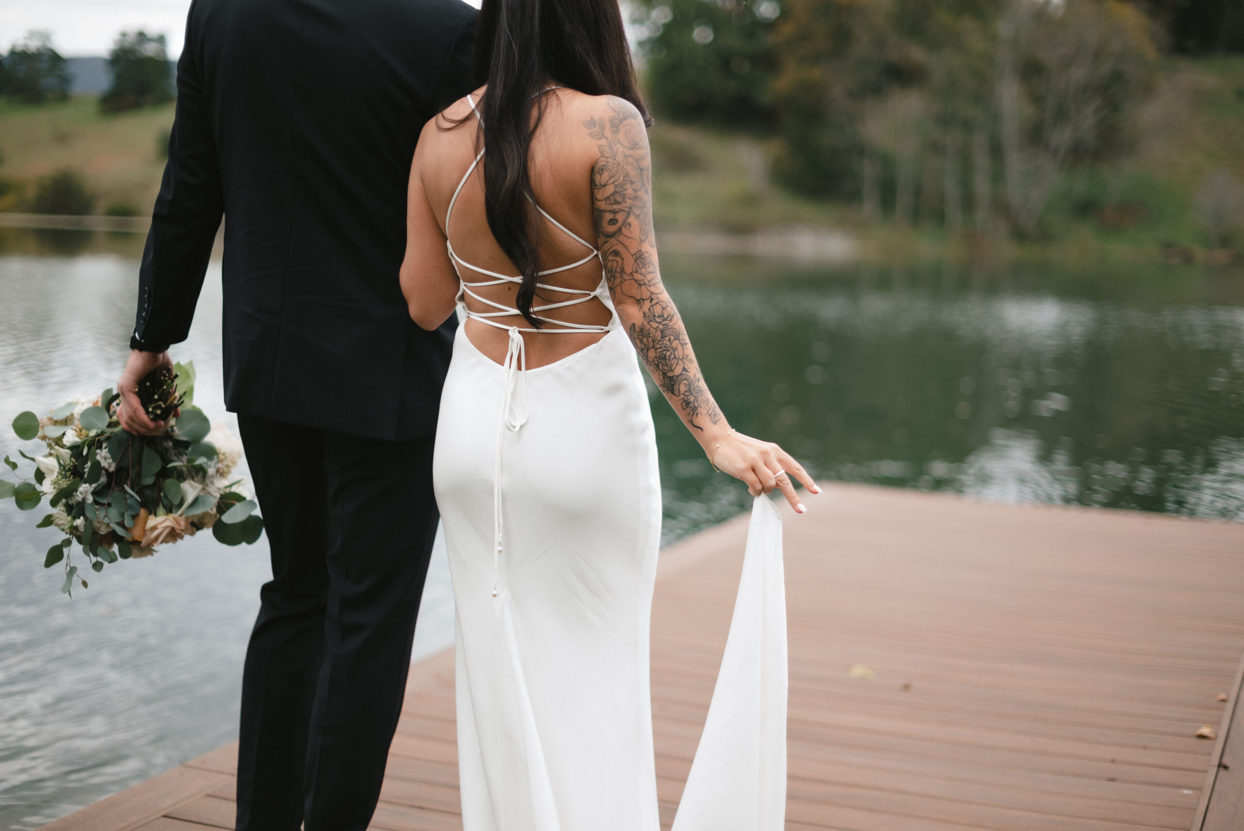 A married couple holds hands on a dock at one of the best Lexington Virginia wedding venues