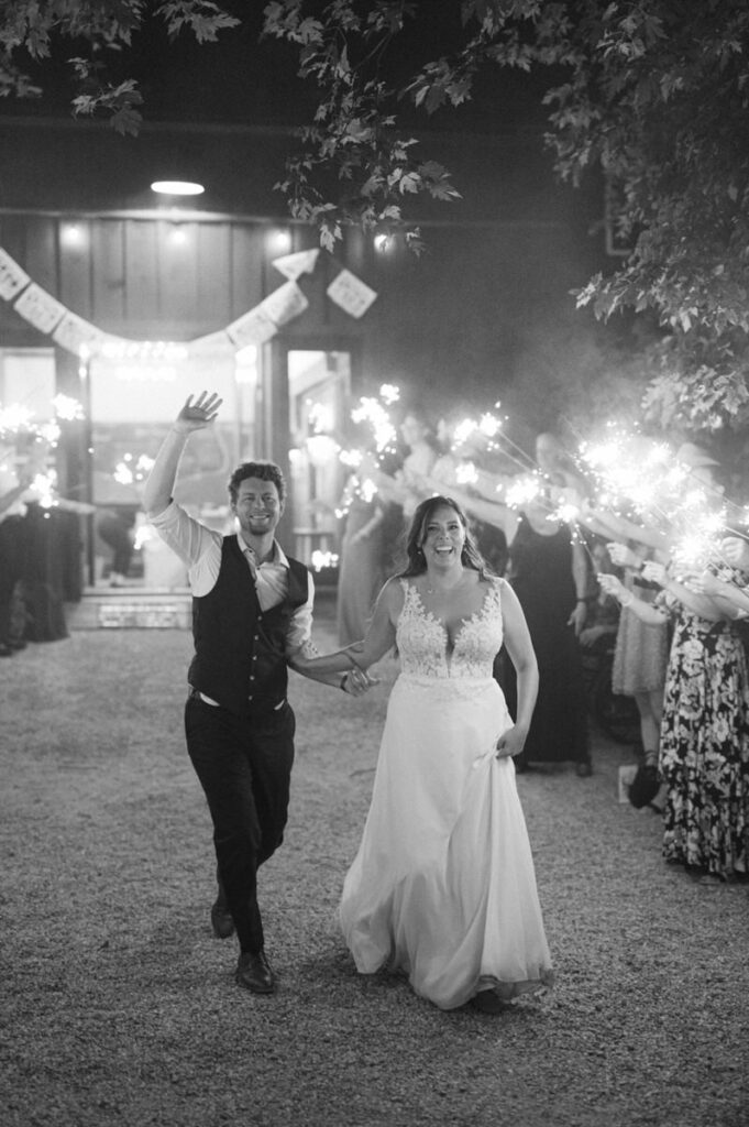 A wedding couple walking through a tunnel of their guests holding sparklers. 