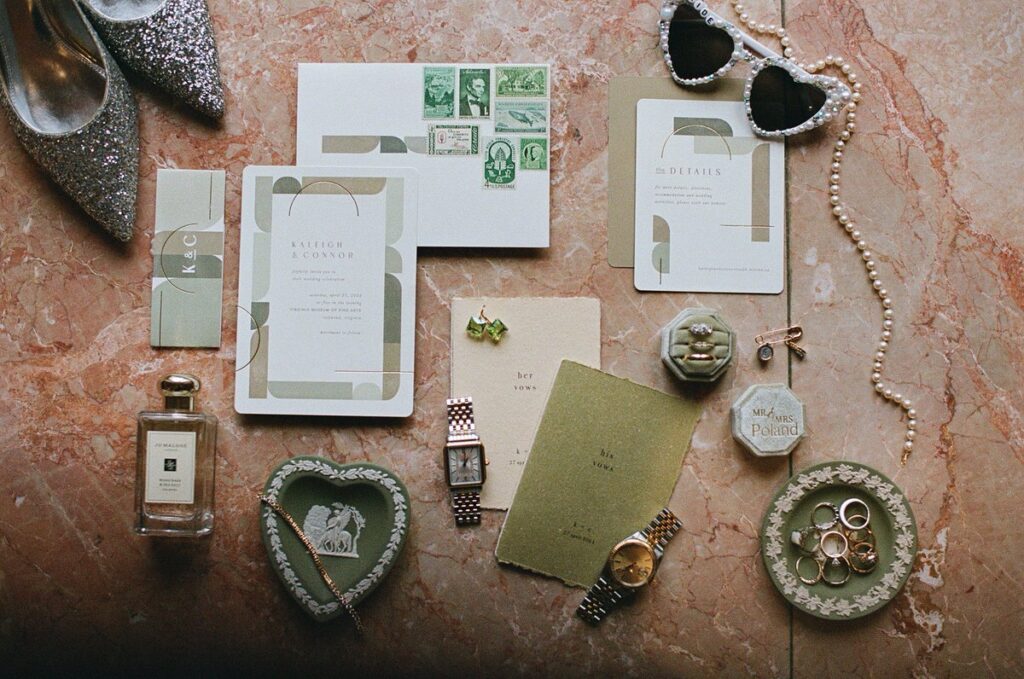 A flatlay showing wedding invitations, jewelry, sunglasses, heels, and perfume. 