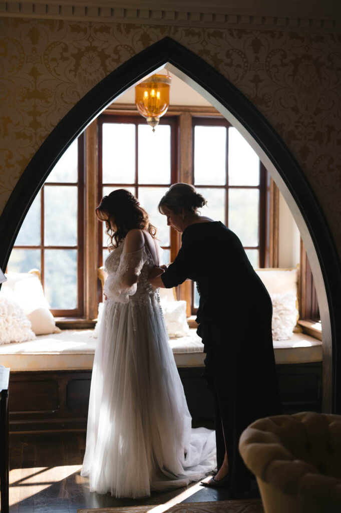 A person helping someone put on their wedding dress. 