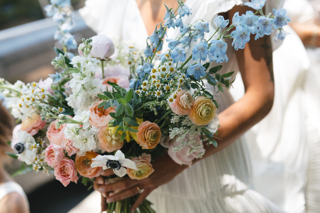 A close up of a person holding a colorful bouquet of flowers 