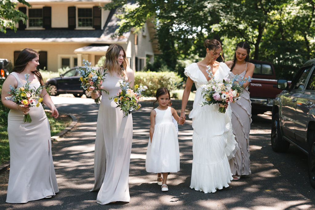 A person walking towards their wedding with their wedding party and flower girl walking with them 