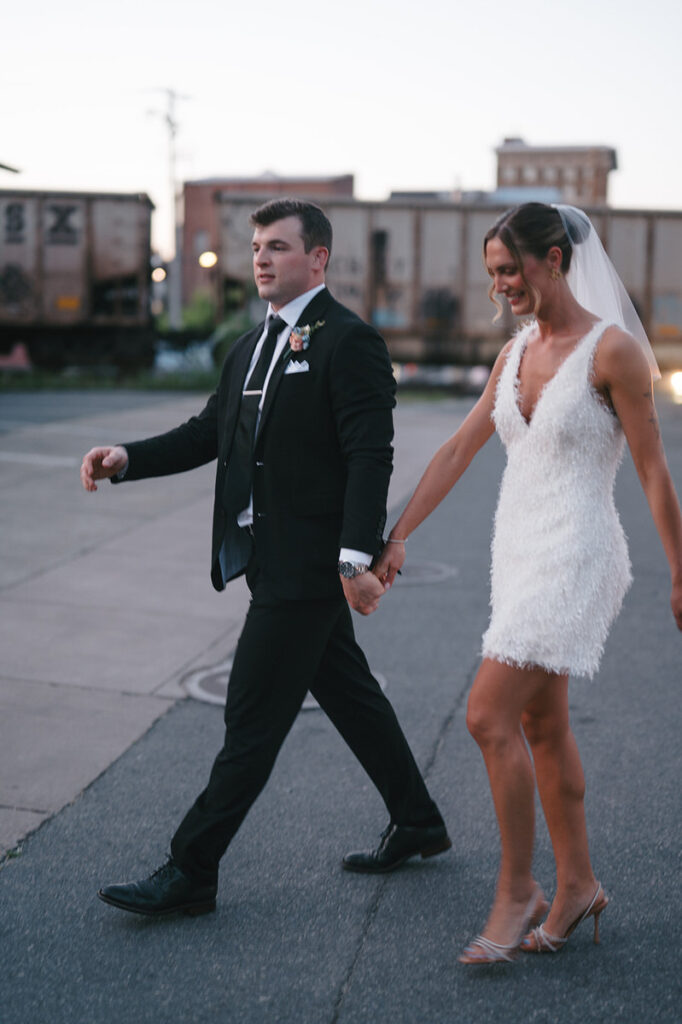 A newlywed couple walking across a street together 