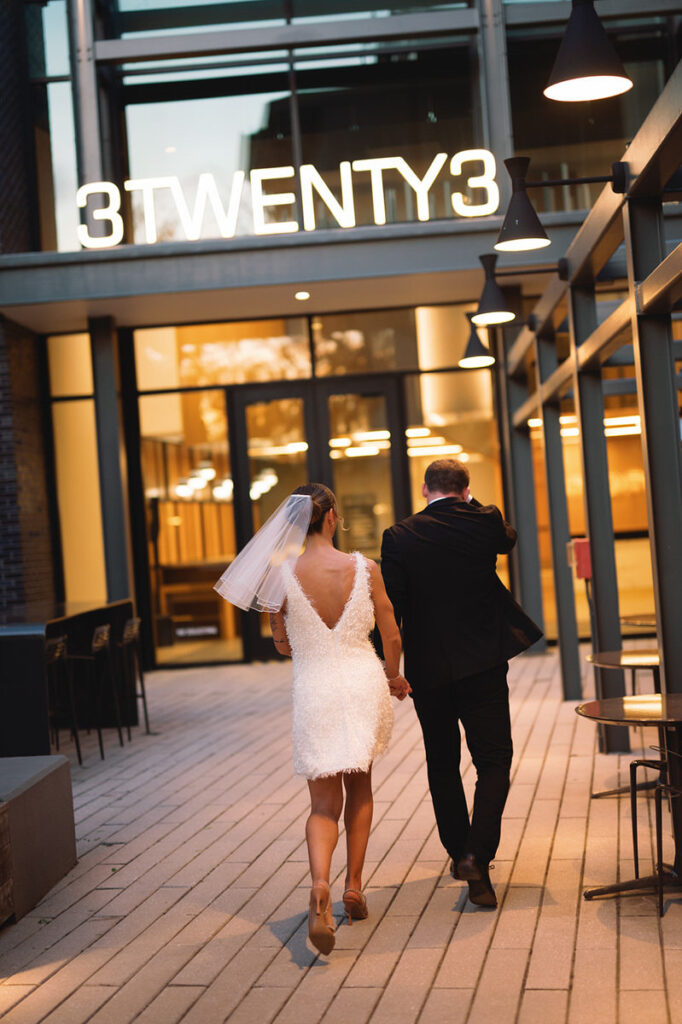 A newlywed couple walking into a building 