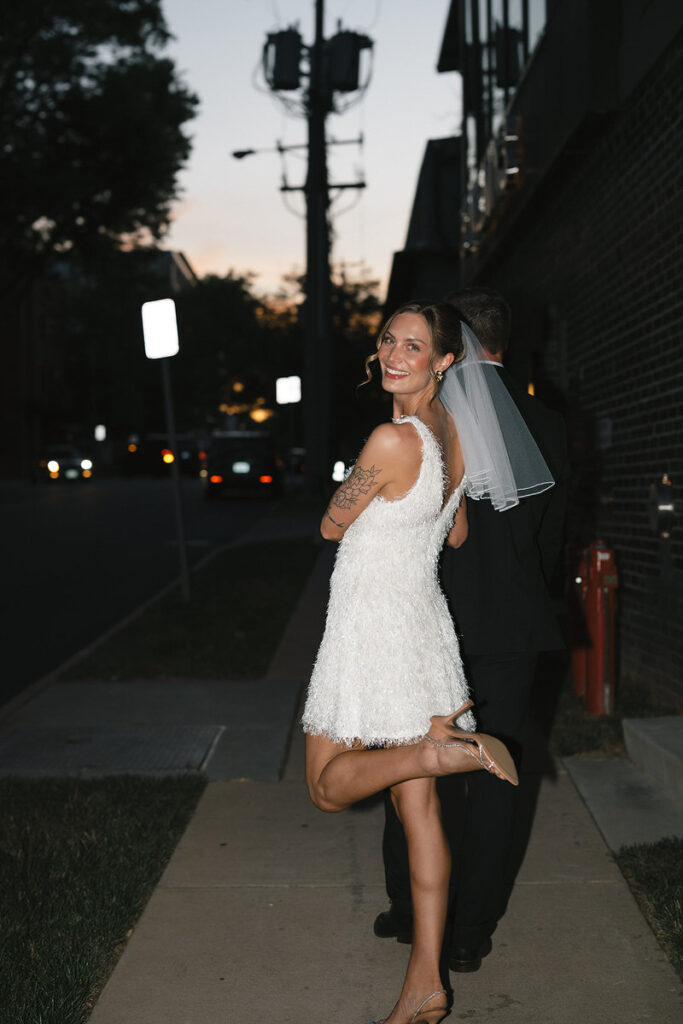 A person looking over their shoulder and kicking one leg up with their arm looped through their partner's. 