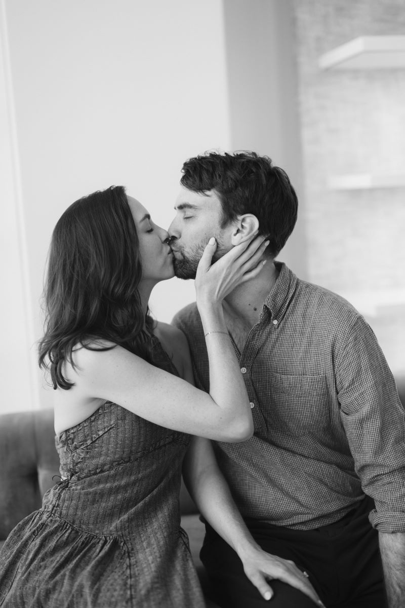 A man and woman are sitting down and kissing each other the woman has her hand on his face 