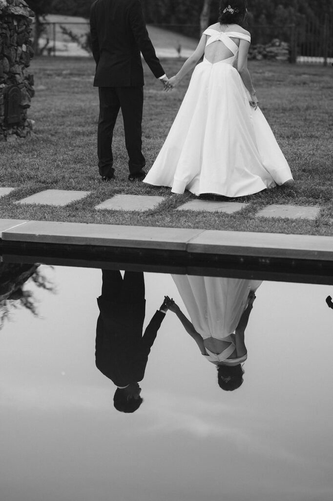 Reflection in a small pond of a couple holding hands and walking together 