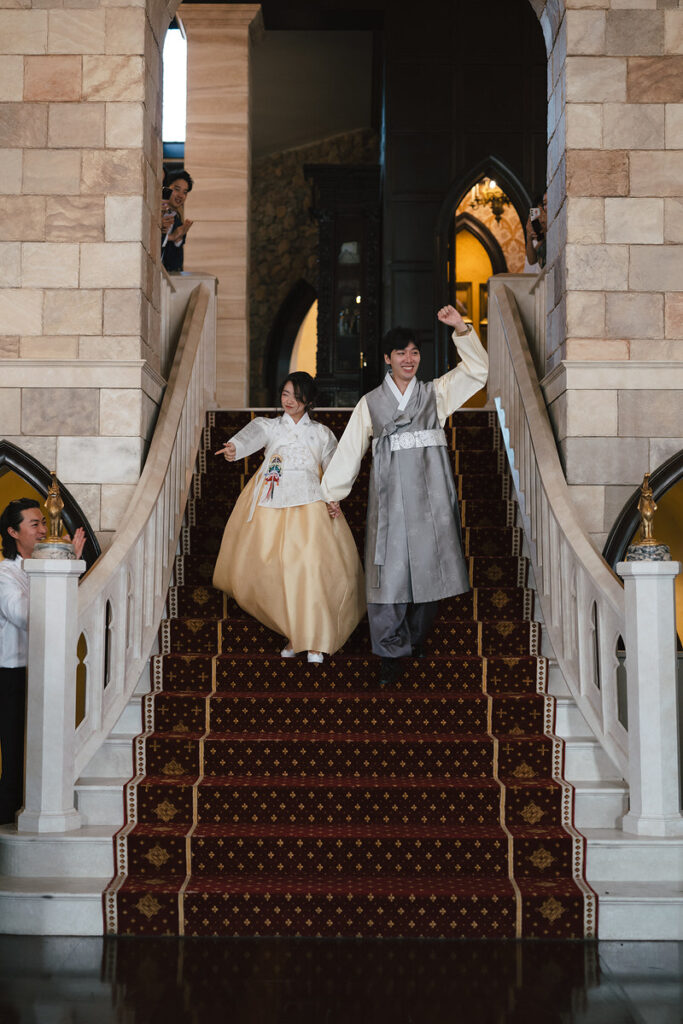 A couple celebrating as they walk down a large staircase 