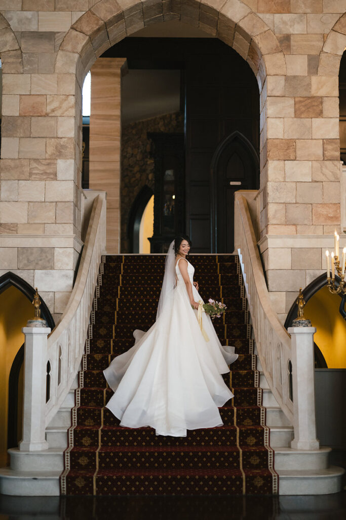 A person in a wedding dress standing on a grand staircase 