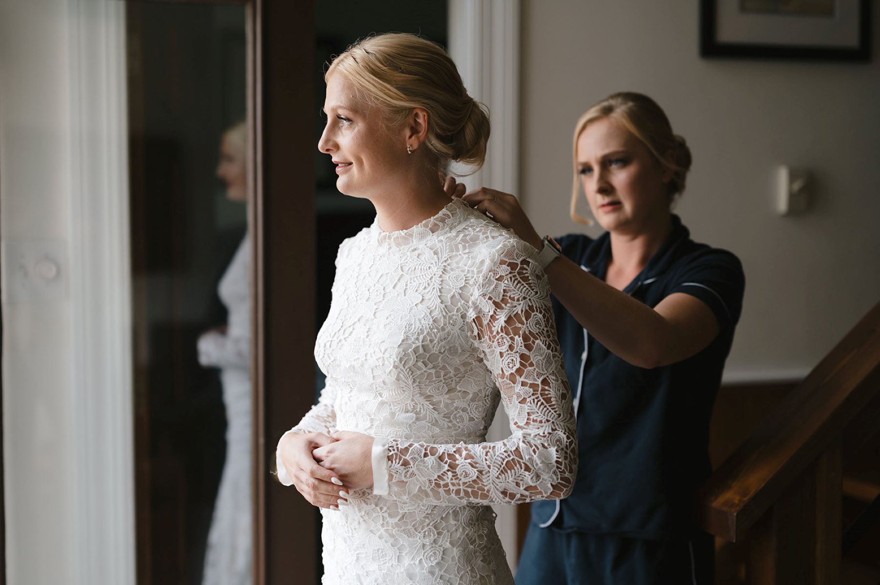 woman fixing the wedding dress of another woman 