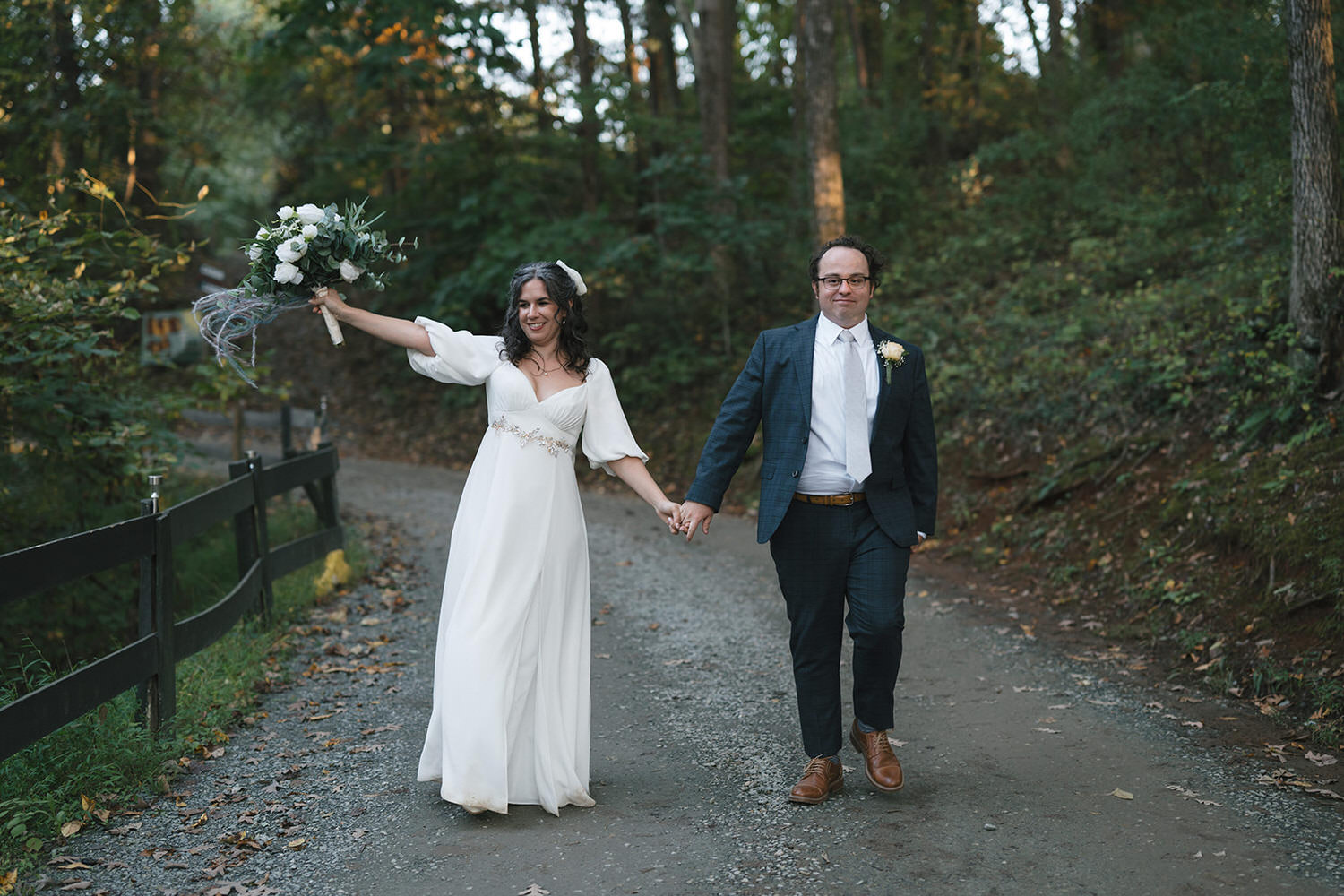 A couple walks hand in hand at a camp holiday trails wedding.